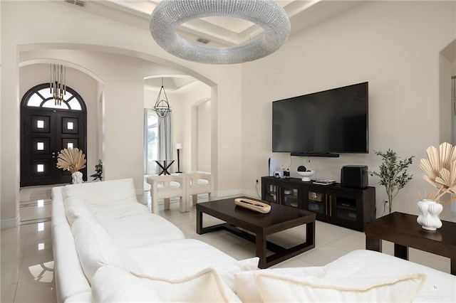 living room featuring arched walkways, light tile patterned floors, a raised ceiling, visible vents, and baseboards