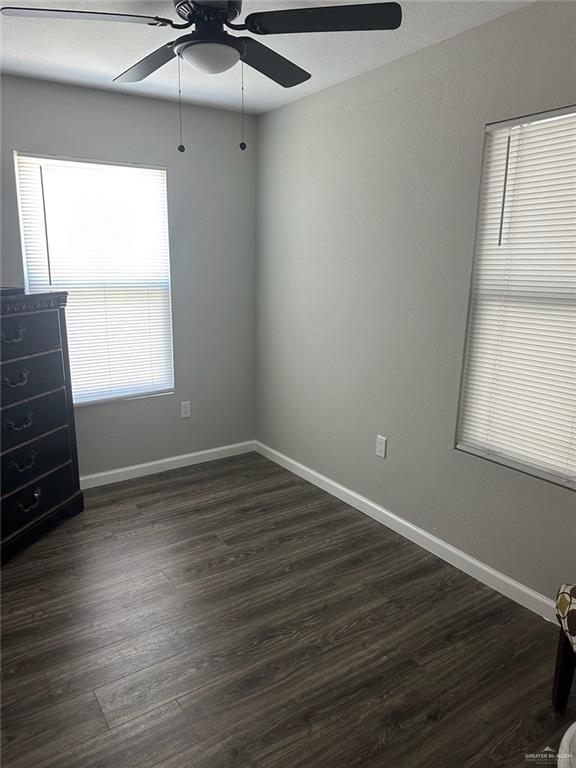 unfurnished room with ceiling fan and dark hardwood / wood-style flooring