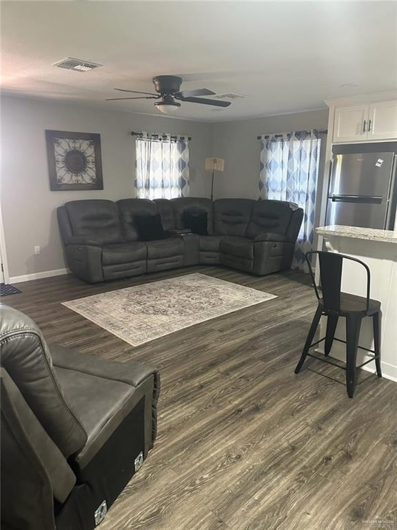 living room with dark hardwood / wood-style flooring, ceiling fan, and plenty of natural light