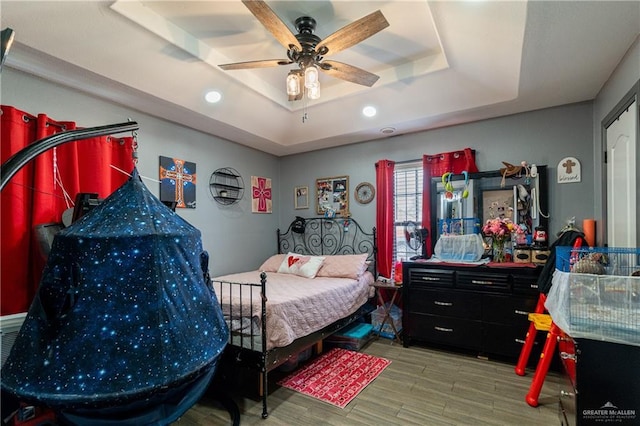 bedroom featuring hardwood / wood-style flooring, ceiling fan, and a raised ceiling