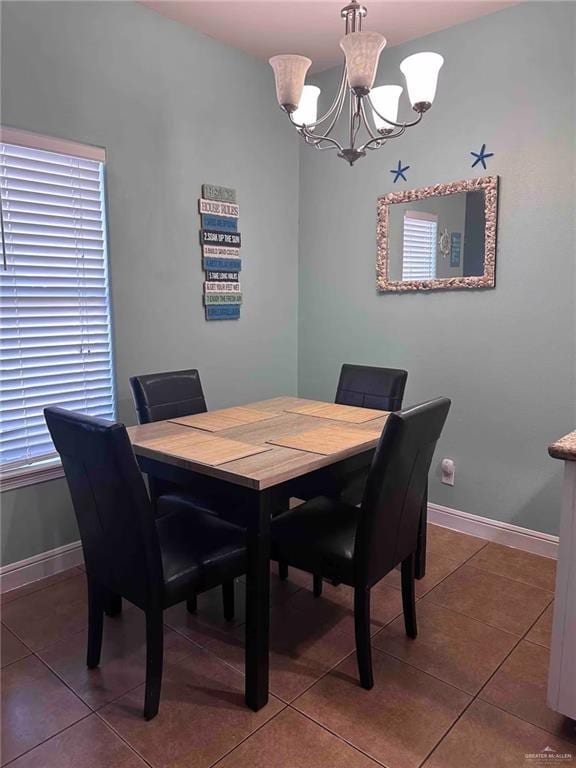 dining area featuring dark tile patterned floors and a chandelier