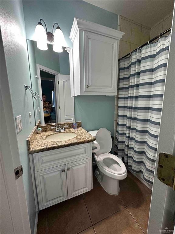 bathroom with a shower with shower curtain, vanity, toilet, and tile patterned flooring