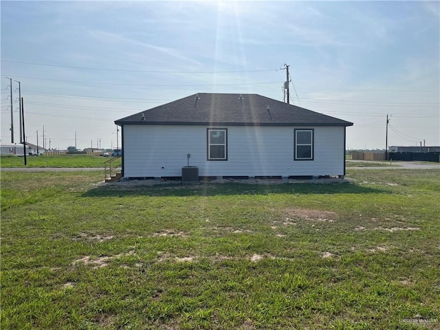 121 N Kentucky St, Mission, TX 78573 - back of house featuring cooling unit, roof with shingles, and a yard