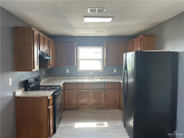 121 N Kentucky St, Mission, TX 78573 - kitchen featuring black appliances, a sink, under cabinet range hood, light wood finished floors, and light countertops