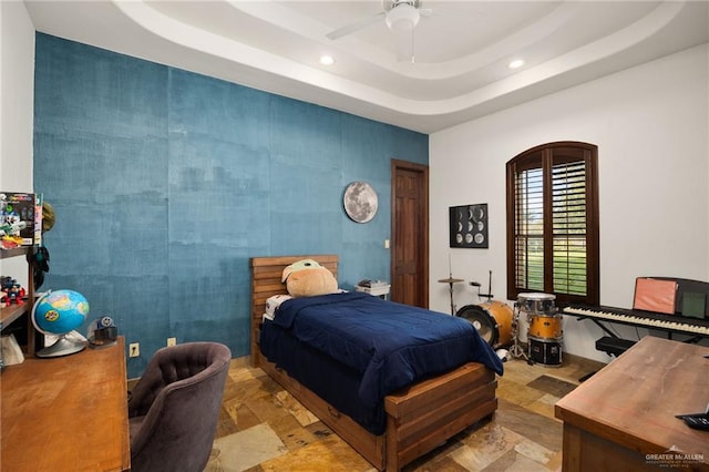 bedroom featuring a raised ceiling and ceiling fan