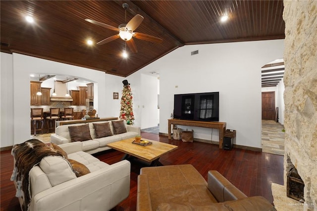 living room with a stone fireplace, vaulted ceiling with beams, wood ceiling, dark hardwood / wood-style flooring, and ceiling fan