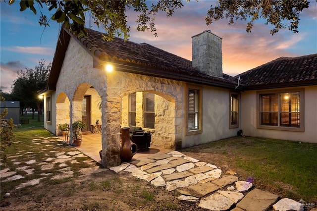 back house at dusk featuring a patio area