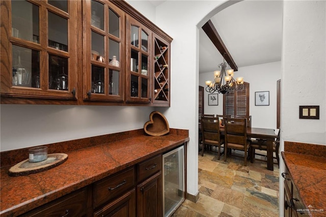 bar featuring wine cooler, dark brown cabinetry, dark stone counters, and pendant lighting