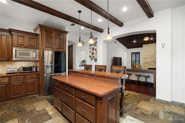 kitchen featuring a breakfast bar, appliances with stainless steel finishes, backsplash, beam ceiling, and a center island