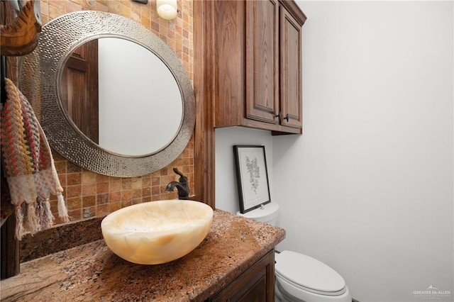 bathroom featuring vanity, backsplash, and toilet