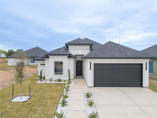 view of front of house featuring a shingled roof, concrete driveway, an attached garage, a front yard, and stucco siding