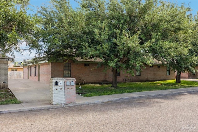 view of front of property featuring driveway, brick siding, and a front lawn