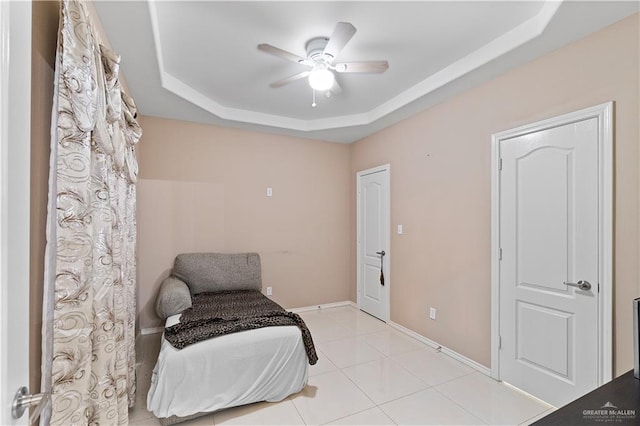 sitting room with light tile patterned floors, a tray ceiling, and ceiling fan