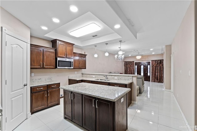 kitchen with a center island, a raised ceiling, sink, and a chandelier