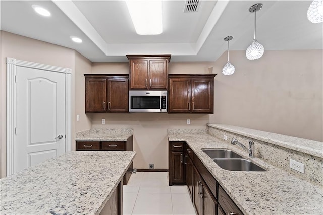 kitchen featuring dark brown cabinetry, light stone countertops, sink, and decorative light fixtures