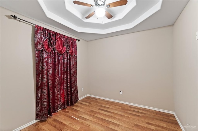 unfurnished room with a tray ceiling, ceiling fan, and hardwood / wood-style flooring