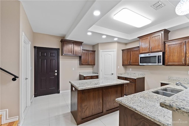 kitchen featuring light stone countertops, sink, a center island, and light tile patterned flooring