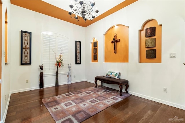 hallway with dark wood-type flooring and an inviting chandelier