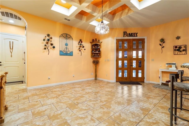 entryway with beamed ceiling, coffered ceiling, french doors, and a skylight