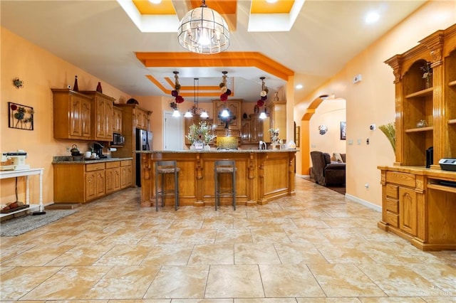 kitchen featuring pendant lighting, a tray ceiling, a breakfast bar area, and kitchen peninsula