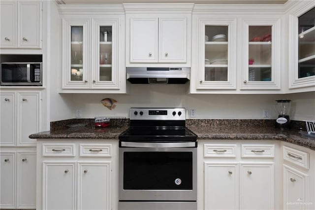 103 W Dolphin St Unit 1B, South Padre Island, TX 78597 - kitchen with range hood, appliances with stainless steel finishes, glass insert cabinets, white cabinetry, and dark stone countertops