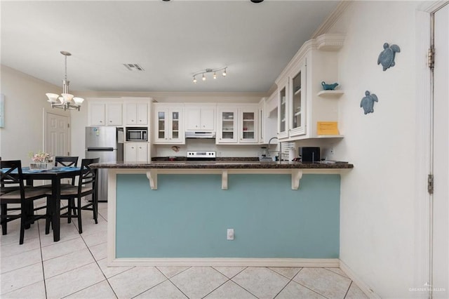 103 W Dolphin St Unit 1B, South Padre Island, TX 78597 - kitchen featuring light tile patterned flooring, visible vents, a kitchen breakfast bar, freestanding refrigerator, and built in microwave