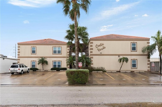 view of front of property featuring a tiled roof, uncovered parking, and stucco siding