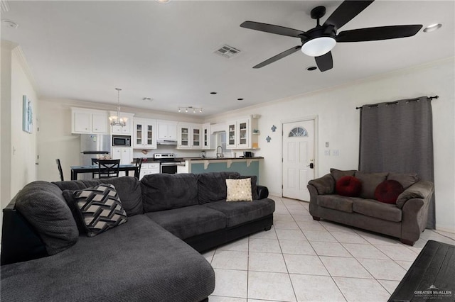 living room with ceiling fan with notable chandelier, visible vents, crown molding, and light tile patterned floors