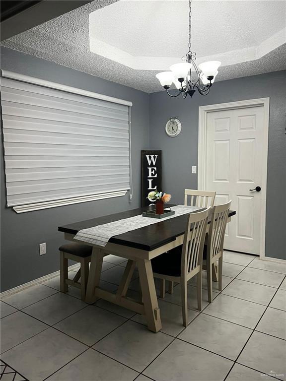 dining area featuring an inviting chandelier, a textured ceiling, baseboards, and light tile patterned flooring