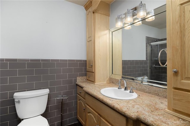 bathroom with vanity, toilet, an enclosed shower, and tile walls