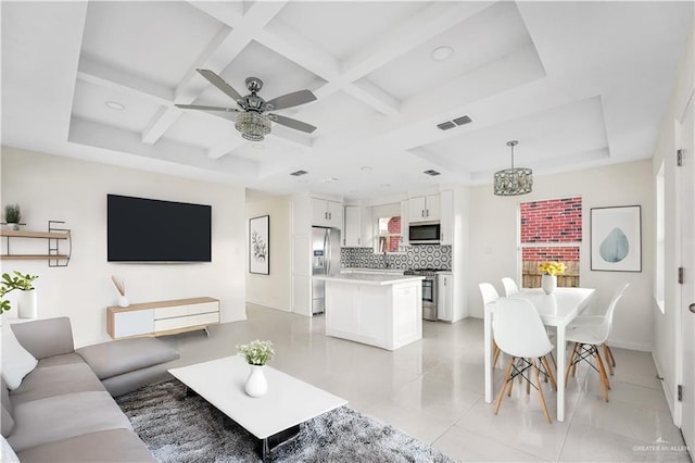 living room with ceiling fan with notable chandelier, a wealth of natural light, coffered ceiling, and light tile patterned flooring