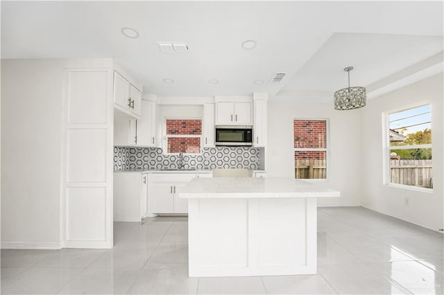 kitchen with white cabinets, decorative light fixtures, and tasteful backsplash