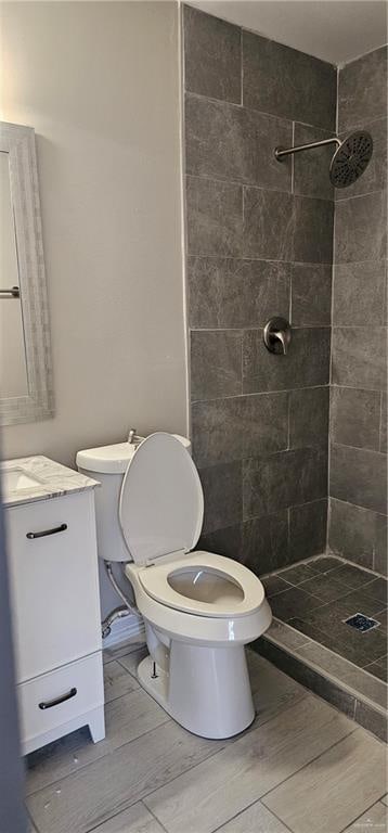 bathroom featuring tiled shower, vanity, and toilet