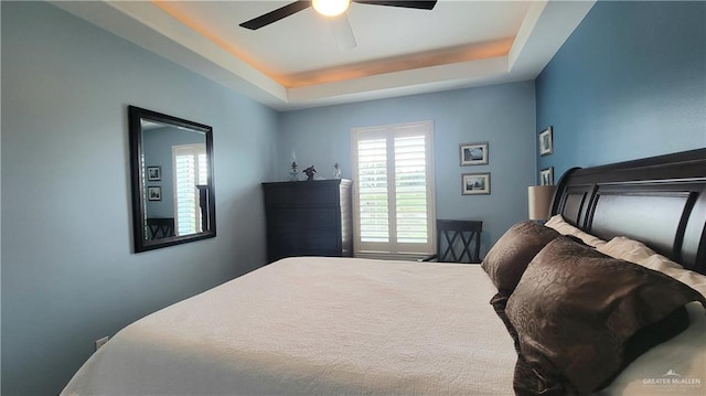 bedroom with carpet flooring, a tray ceiling, and ceiling fan