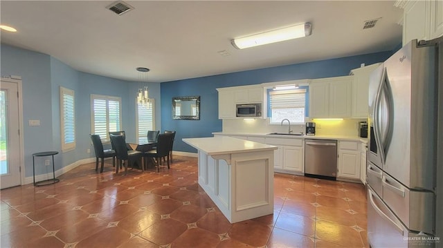 kitchen featuring sink, a center island, pendant lighting, white cabinets, and appliances with stainless steel finishes