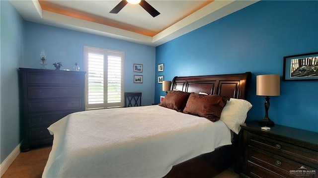 carpeted bedroom with a tray ceiling and ceiling fan