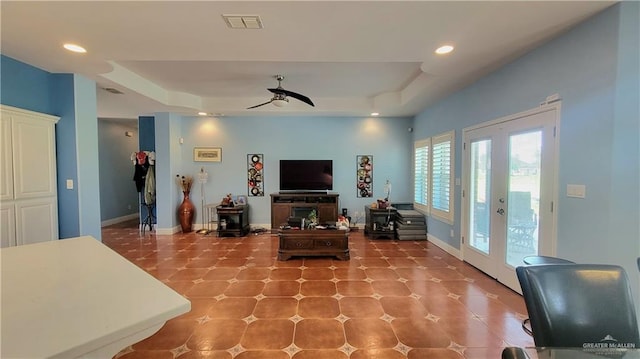 living room with french doors, a tray ceiling, and ceiling fan