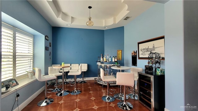 home office with indoor bar, a raised ceiling, dark tile patterned floors, and beverage cooler