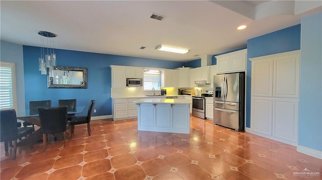 kitchen featuring a center island, white cabinets, sink, decorative light fixtures, and stainless steel appliances