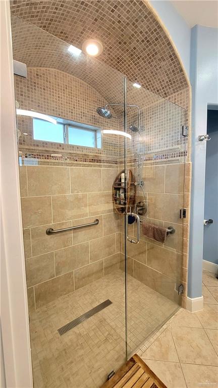 bathroom with tile patterned floors, vaulted ceiling, and a shower with door