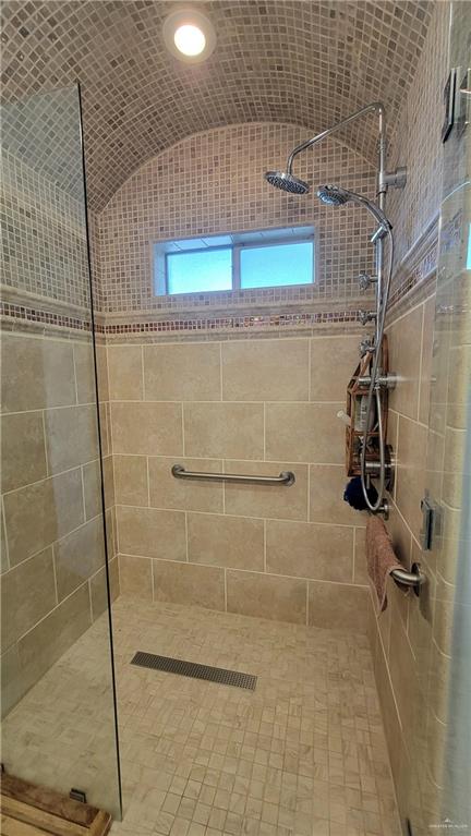 bathroom with tiled shower and vaulted ceiling