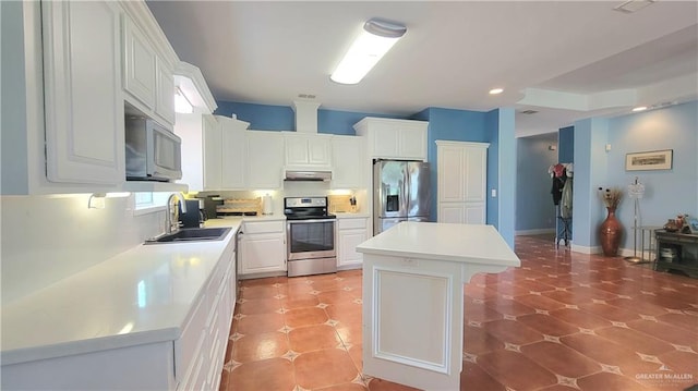 kitchen with sink, appliances with stainless steel finishes, a kitchen island, a kitchen bar, and white cabinetry