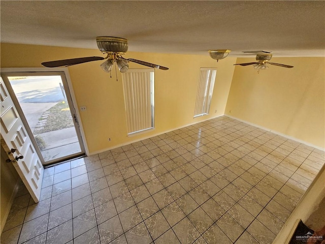 tiled empty room with ceiling fan and a textured ceiling