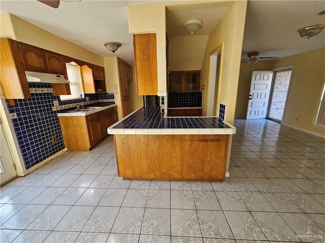 kitchen featuring light tile patterned floors, ceiling fan, a healthy amount of sunlight, tile countertops, and kitchen peninsula