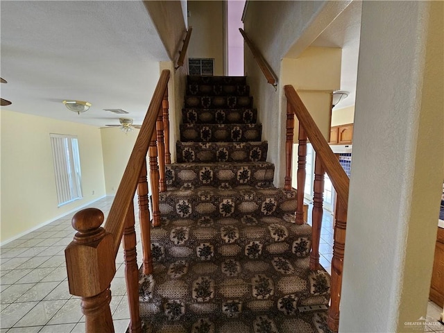 stairway featuring ceiling fan and tile patterned flooring