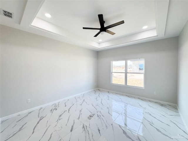 spare room with ceiling fan and a raised ceiling