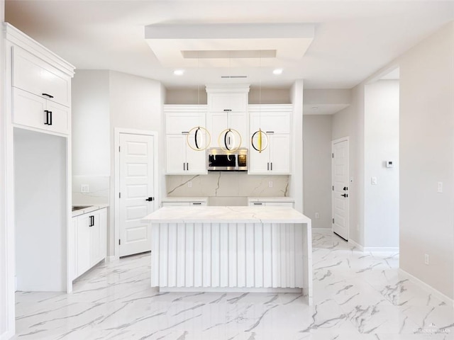 kitchen with white cabinetry, backsplash, light stone counters, and a kitchen island