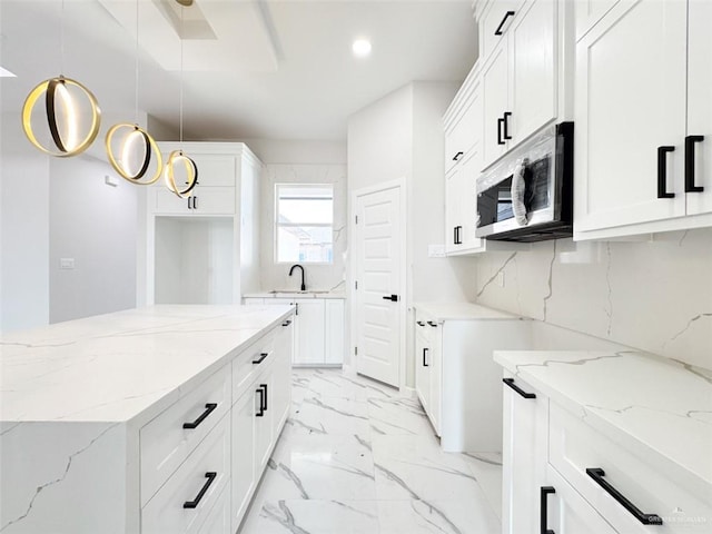 kitchen with pendant lighting, backsplash, white cabinetry, and light stone countertops