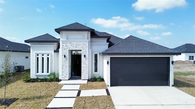 view of front of home with a garage, a front yard, and central air condition unit