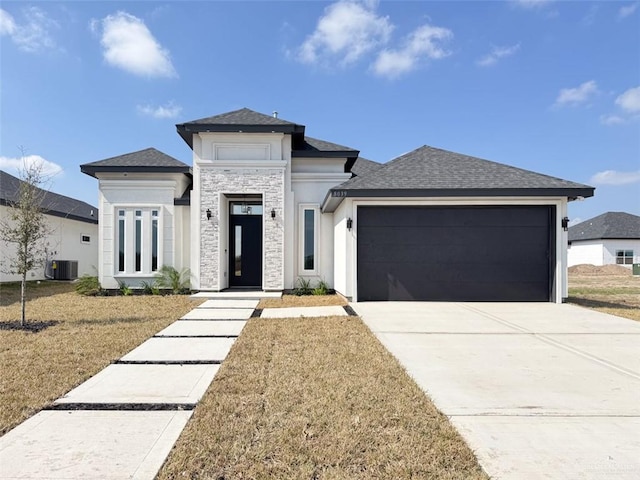 view of front of property with central AC unit, a garage, and a front lawn